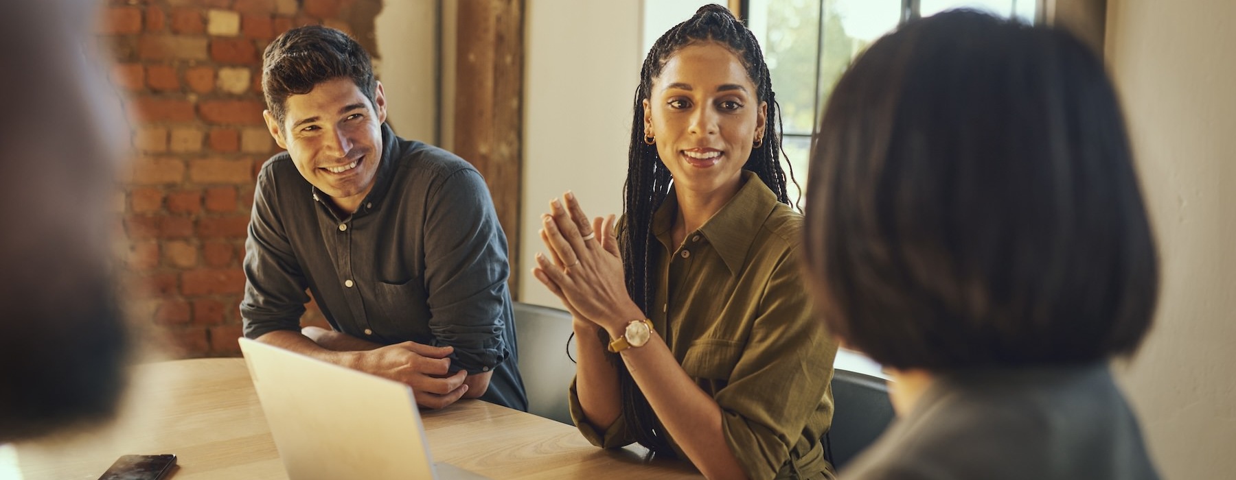 a group of people talking at a table with a laptop